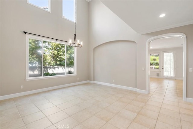 spare room featuring a towering ceiling, arched walkways, light tile patterned floors, baseboards, and a notable chandelier