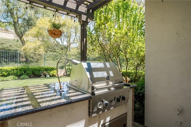 view of patio featuring fence, a pergola, exterior kitchen, and a grill