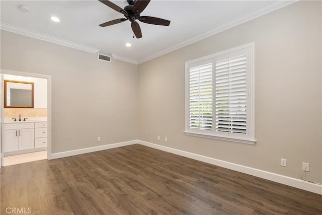 unfurnished bedroom featuring crown molding, a sink, baseboards, wood finished floors, and visible vents