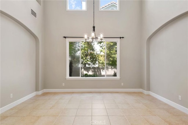 unfurnished dining area with an inviting chandelier, visible vents, light tile patterned flooring, baseboards, and a high ceiling