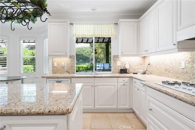 kitchen featuring light stone countertops, a sink, light tile patterned floors, ornamental molding, and white cabinetry