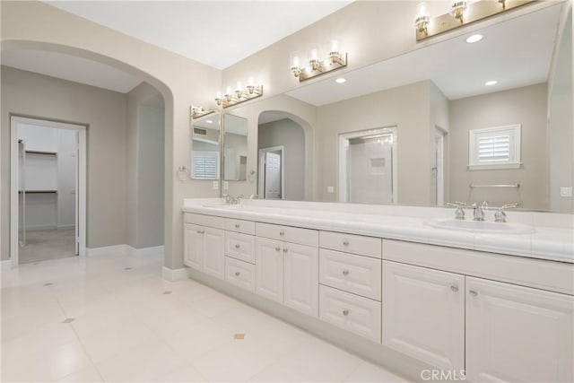 bathroom featuring double vanity, a sink, and baseboards