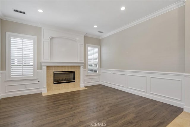 unfurnished living room featuring a decorative wall, wainscoting, dark wood finished floors, and visible vents