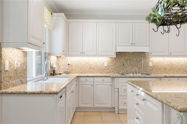 kitchen with light stone countertops, a sink, white cabinets, under cabinet range hood, and white appliances