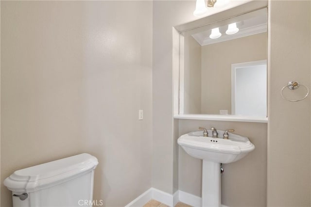bathroom featuring crown molding, baseboards, and toilet