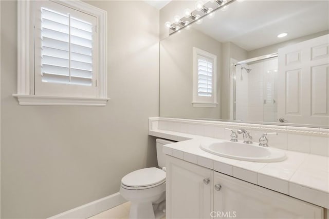 bathroom with tile patterned flooring, baseboards, vanity, toilet, and tiled shower