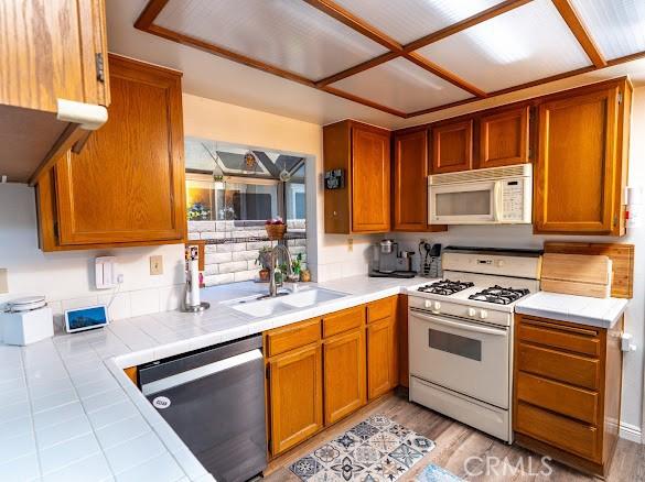 909 Shady Ln, Glendora, CA 91740 - kitchen featuring white appliances, a sink, tile counters, brown cabinets, and light wood-style floors
