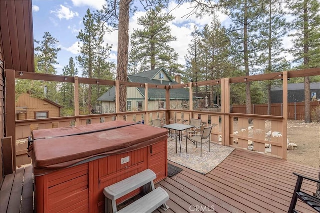 wooden deck featuring a hot tub, fence, and outdoor dining space