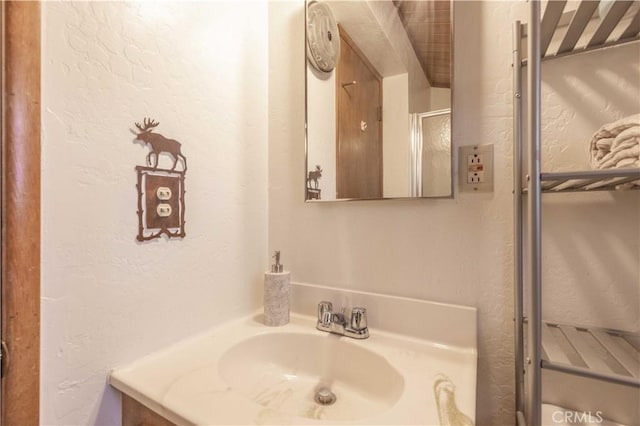 bathroom with a textured wall and vanity