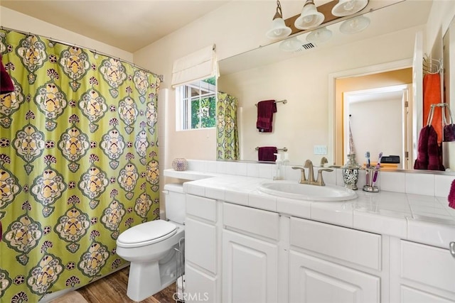 bathroom with toilet, curtained shower, wood finished floors, and vanity