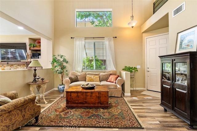 sitting room featuring a wealth of natural light, a high ceiling, wood finished floors, and visible vents