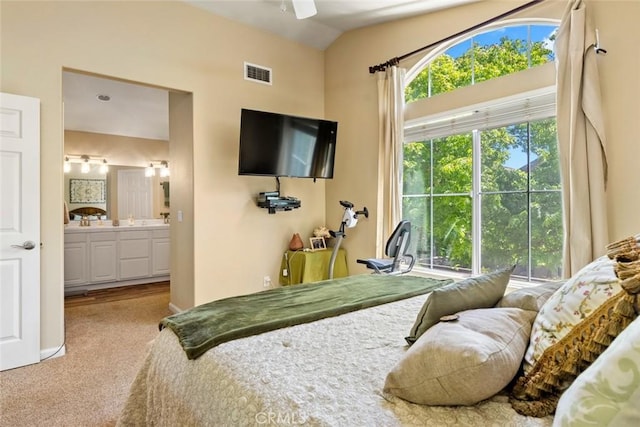 bedroom with visible vents, ensuite bath, carpet floors, and lofted ceiling