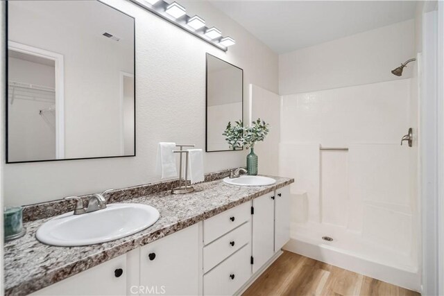 1148 Arlington Ct, Rosamond, CA 93560 - full bath with double vanity, walk in shower, a sink, and wood finished floors