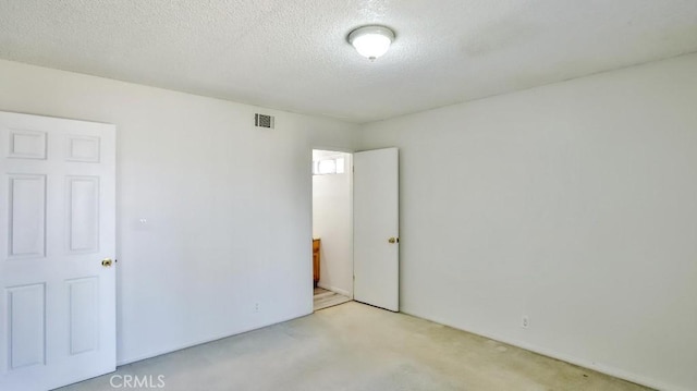 unfurnished bedroom with carpet flooring, a textured ceiling, and visible vents