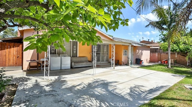 back of house featuring washer and dryer, a patio area, stucco siding, and fence