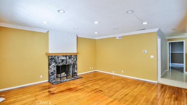 unfurnished living room with baseboards, ornamental molding, wood finished floors, and a fireplace