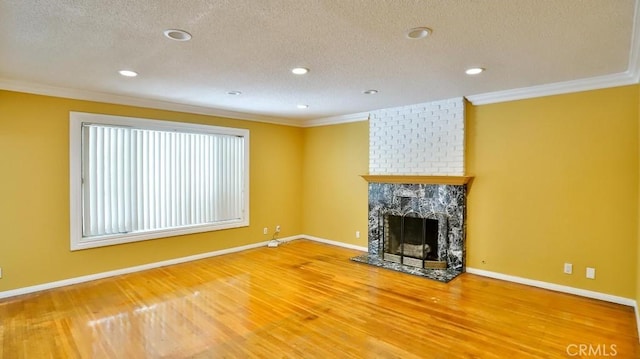 unfurnished living room featuring ornamental molding, a fireplace, a textured ceiling, and wood finished floors