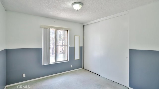 unfurnished room with baseboards, carpet, and a textured ceiling