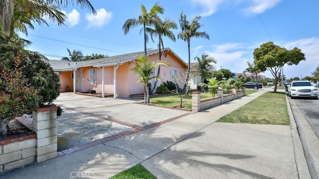 view of front facade featuring stucco siding, driveway, and a front yard