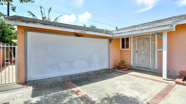 view of exterior entry with concrete driveway, an attached garage, and stucco siding