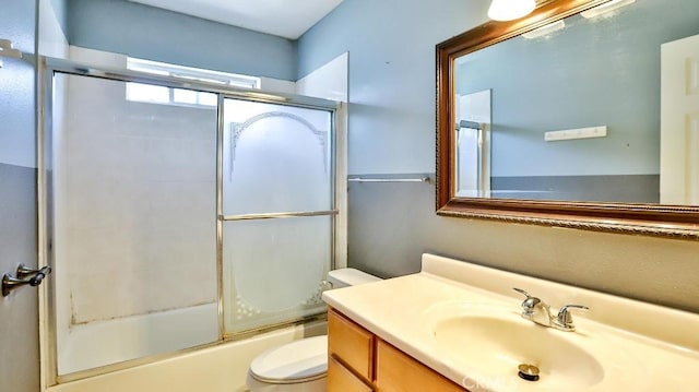 bathroom featuring toilet, combined bath / shower with glass door, and vanity