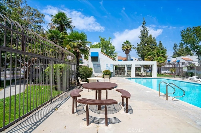 community pool with a patio area and fence