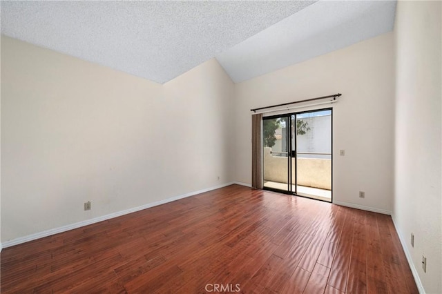 spare room with baseboards, vaulted ceiling, and wood finished floors