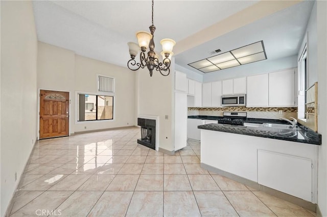 kitchen featuring white cabinets, an inviting chandelier, a sink, stainless steel appliances, and backsplash