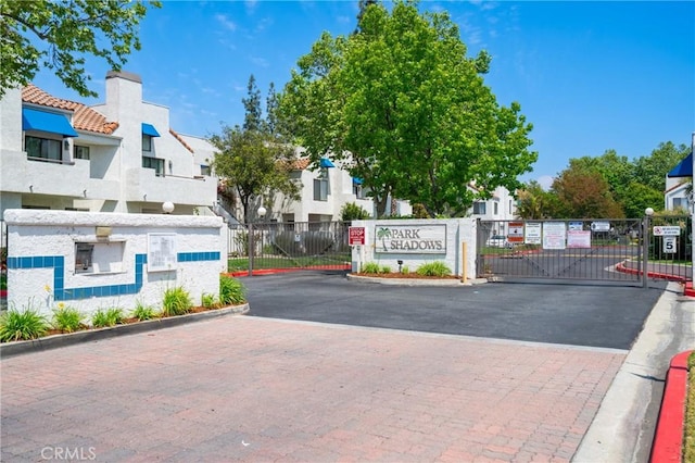 view of street featuring curbs, a gated entry, a gate, and a residential view