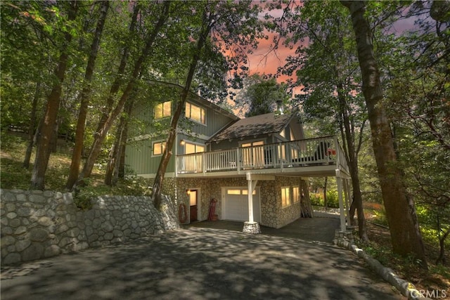 28805 N Shore Rd, Lake Arrowhead, CA 92352 - view of front of home featuring concrete driveway, an attached garage, a wooden deck, and stone siding