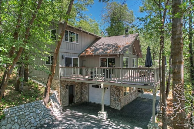28805 N Shore Rd, Lake Arrowhead, CA 92352 - back of property featuring stone siding, a deck, a chimney, an attached garage, and driveway