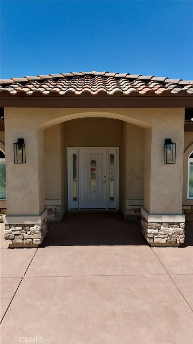 view of exterior entry featuring stucco siding and a tile roof