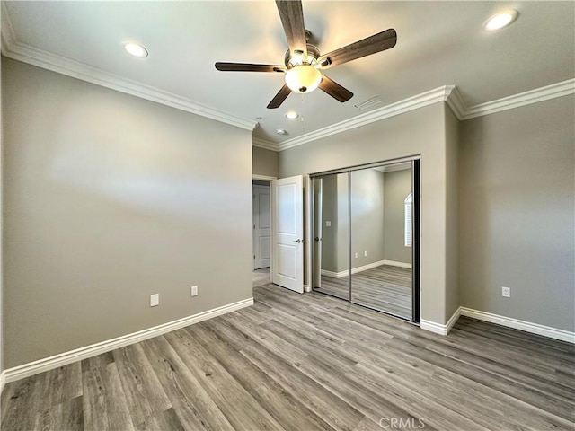 unfurnished bedroom with baseboards, visible vents, wood finished floors, and a closet