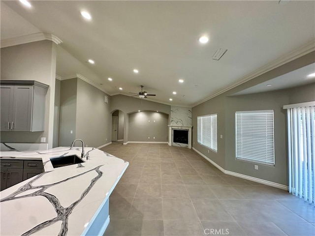 kitchen featuring ceiling fan, gray cabinets, arched walkways, a sink, and ornamental molding