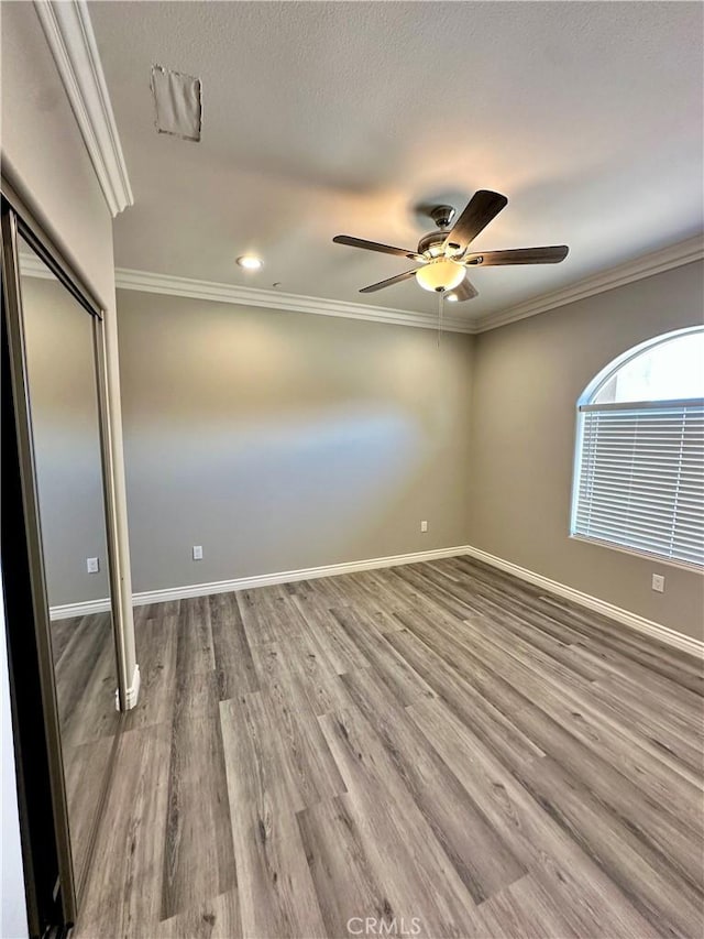 unfurnished bedroom featuring baseboards, ornamental molding, a ceiling fan, and wood finished floors