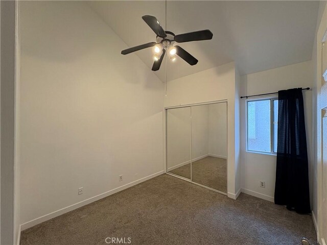 unfurnished bedroom featuring carpet floors, baseboards, a closet, ceiling fan, and high vaulted ceiling