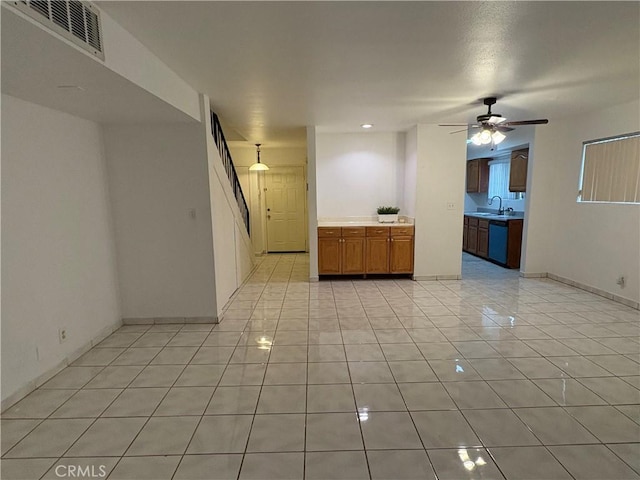 empty room featuring light tile patterned floors, a sink, a ceiling fan, stairway, and baseboards
