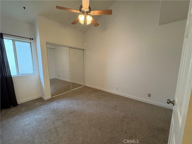 unfurnished bedroom featuring carpet flooring, vaulted ceiling, baseboards, a closet, and ceiling fan