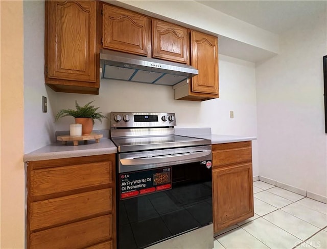 kitchen featuring stainless steel electric stove, under cabinet range hood, light countertops, brown cabinets, and light tile patterned floors