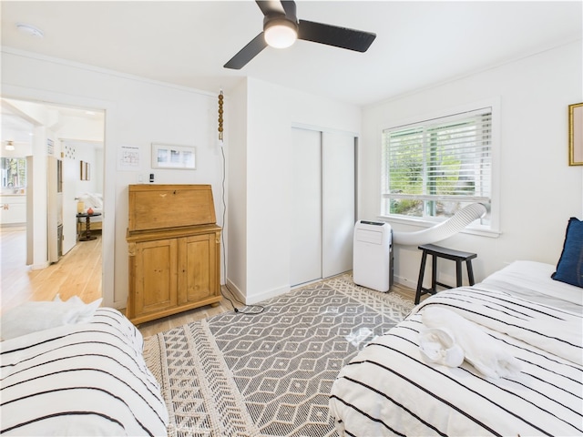 bedroom featuring light wood-type flooring, a ceiling fan, baseboards, and a closet