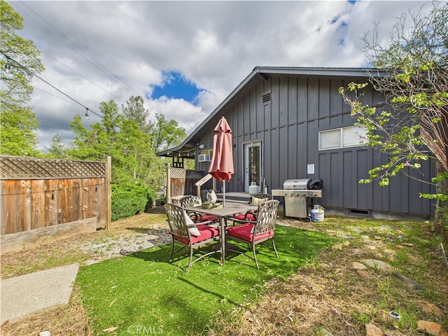 back of property with board and batten siding, fence, and a yard