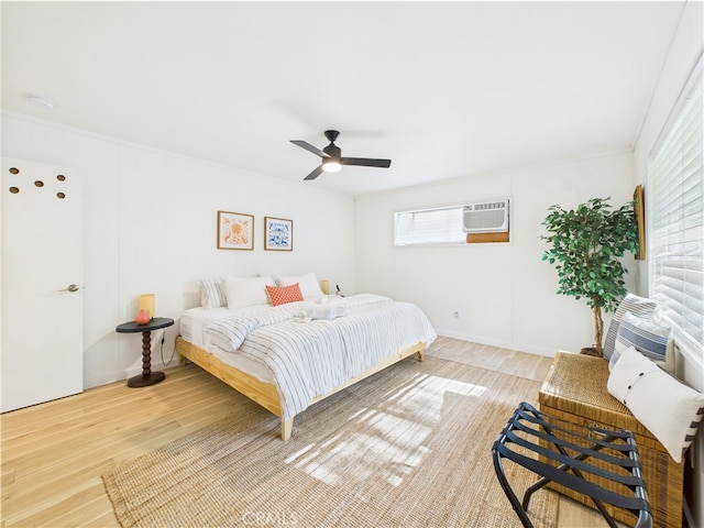 bedroom featuring a wall mounted AC, a ceiling fan, and wood finished floors