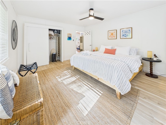 bedroom featuring ceiling fan, ornamental molding, wood finished floors, and a closet