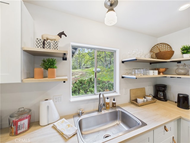 kitchen featuring a sink, white cabinets, and open shelves