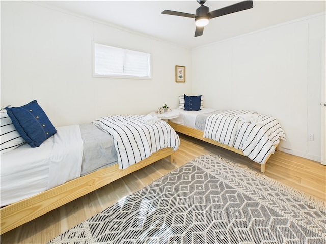 bedroom with crown molding, ceiling fan, and wood finished floors
