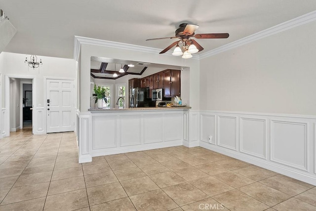 kitchen featuring ceiling fan with notable chandelier, freestanding refrigerator, stainless steel microwave, light tile patterned floors, and ornamental molding