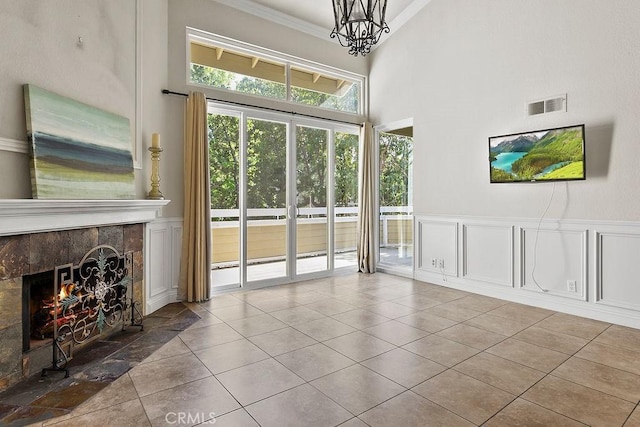 3630 S Bear St Unit 67, Santa Ana, CA 92704 - unfurnished living room featuring a tile fireplace, ornamental molding, tile patterned flooring, a towering ceiling, and a decorative wall