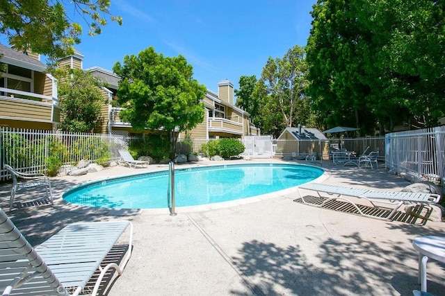 pool with a patio, an outdoor structure, and fence