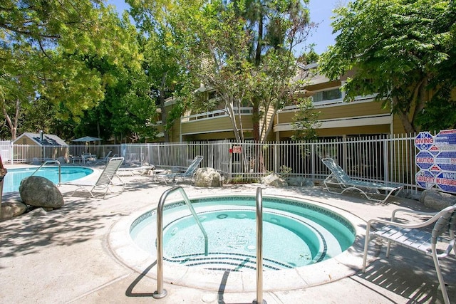 community pool with a community hot tub, a patio area, and fence