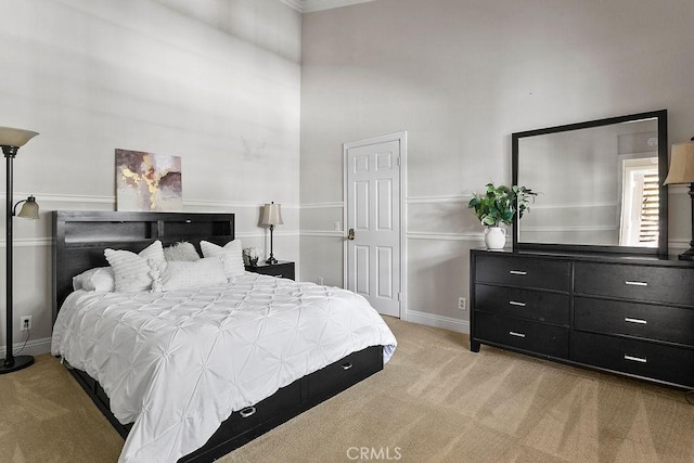 bedroom featuring crown molding, baseboards, light carpet, and a towering ceiling